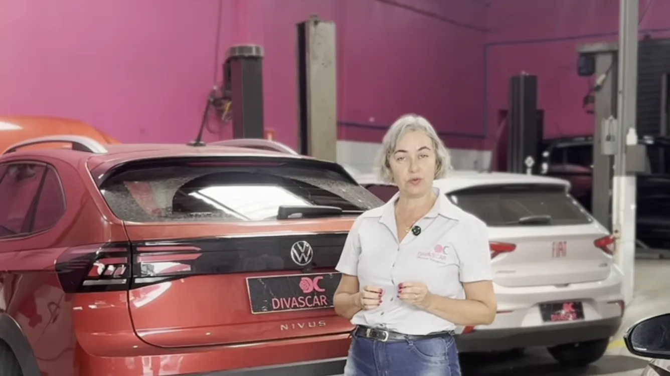 A Joelma ao lado de um VW Nivus vermelho na oficina